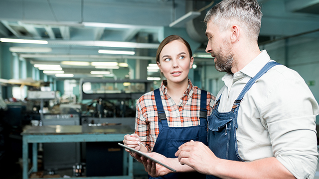 机械车间里的两个人在平板电脑设备上工作。