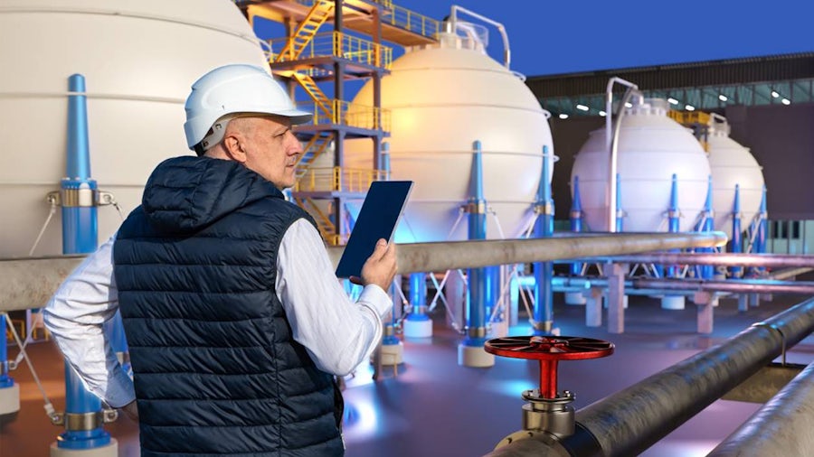 Industrial engineer monitors a green hydrogen production facility using Siemens advanced digital tools from tablet. 