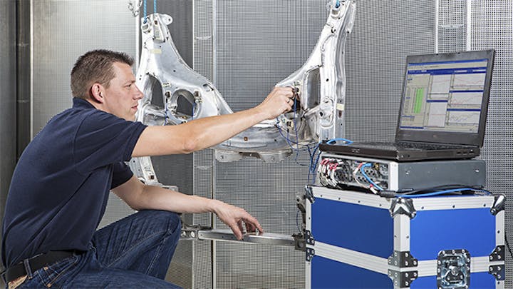 An engineer running an experimental modal analysis on a structure connected to a laptop.