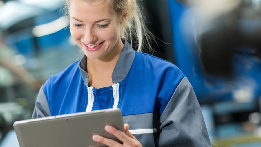 An engineer uses a computer tablet to operate manufacturing execution software from the cloud.