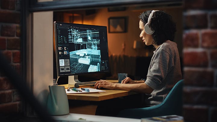 一个戴着耳机的女人坐在电脑前,运行着一个设计程序