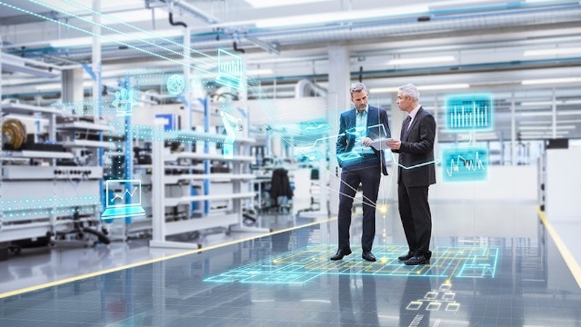 Two people on a shop floor, interacting with graphic representations of data.