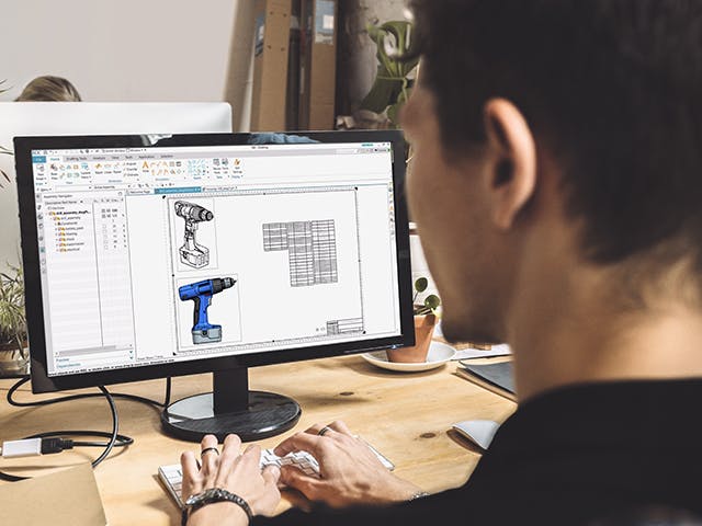 A man using NX Drafting and Layout software by Siemens.