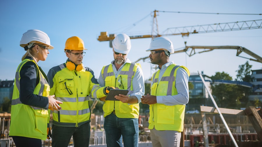 Engineers from different design teams meeting about product development in a heavy equipment outdoor setting