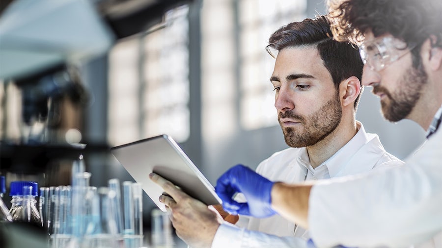 Two scientists use a digital tablet in a laboratory.