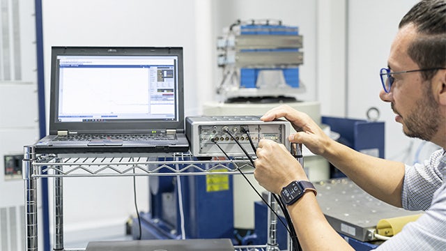 A man using a Simcenter SCADAS hardware device with the laptop executing vibration and shock testing.