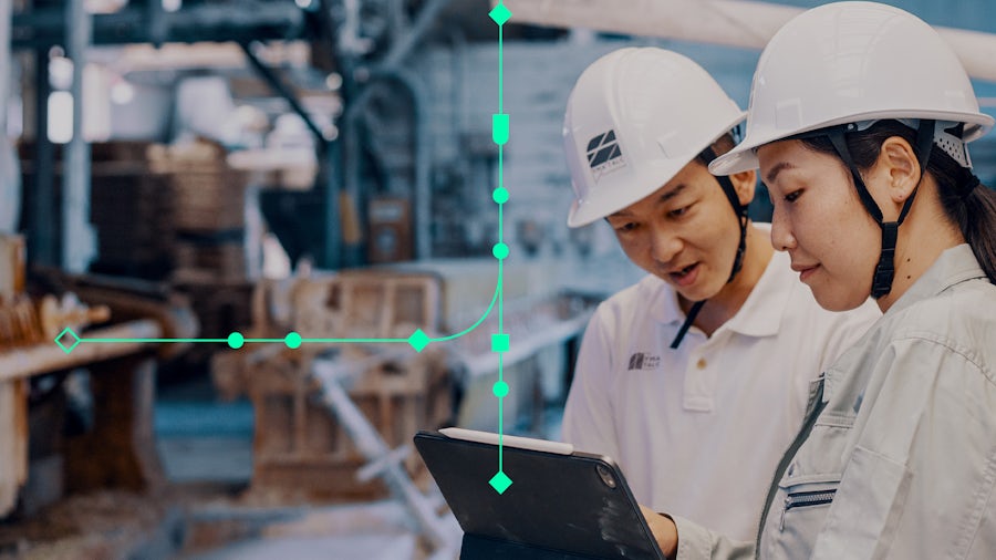 Two person looking at a computer and wearing hard hats