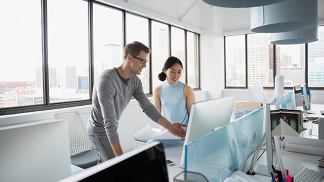 Zwei Personen arbeiten an einem Desktop-Computer zusammen