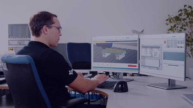 Man sitting at a desk with two monitors using Siemens software.