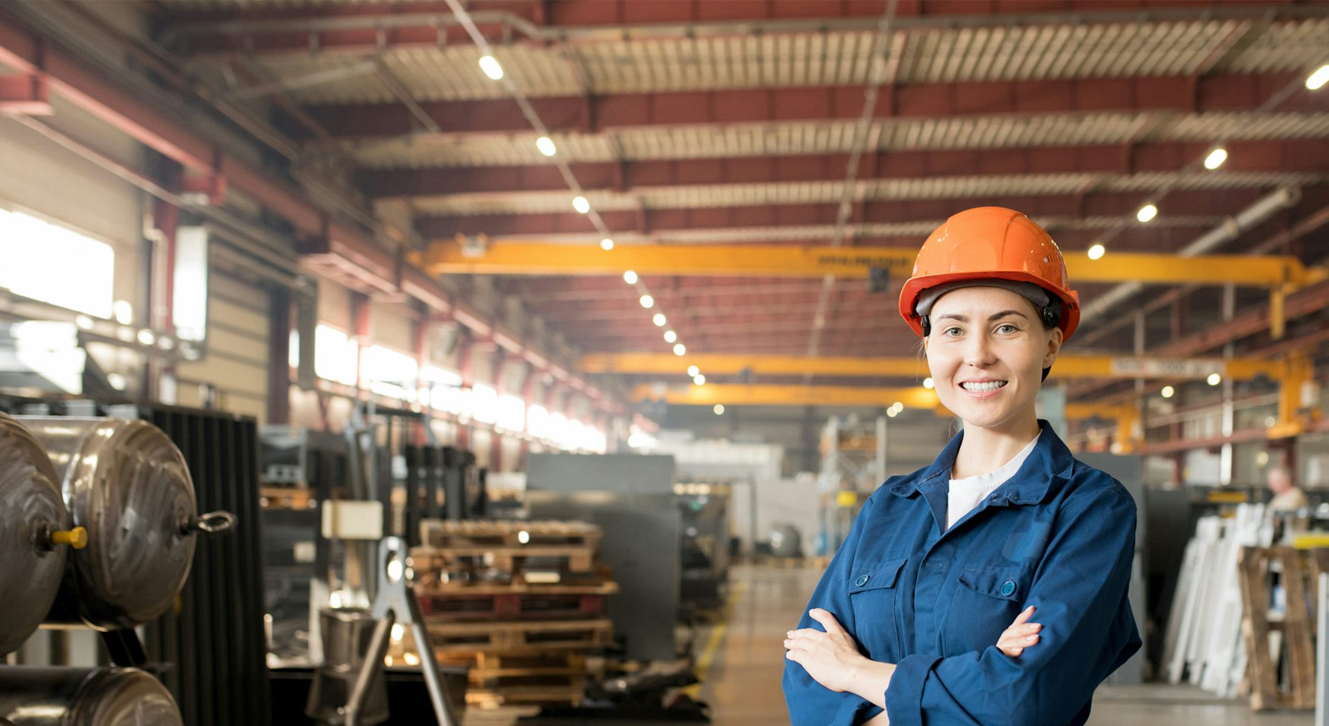 A woman wearing PPE gear is standing in a factory.​