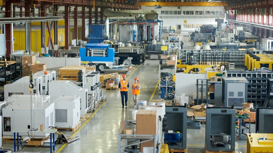 Two engineers in safety vests walking in a manufacturing facility