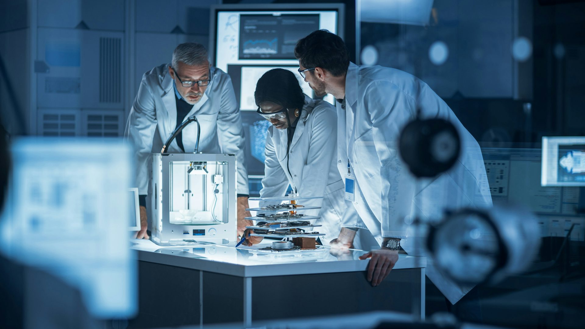 Three engineers looking at a medical device part in a laboratory.
