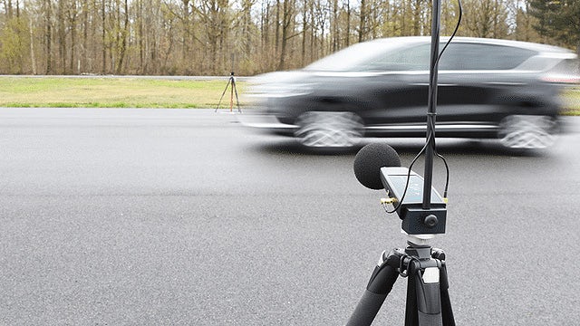 A microphone checking the pass-by noise level of a moving car