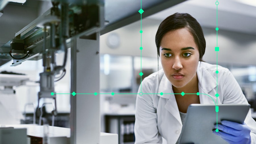 Woman engineer looking at manufacturing machinery while holding a tablet.