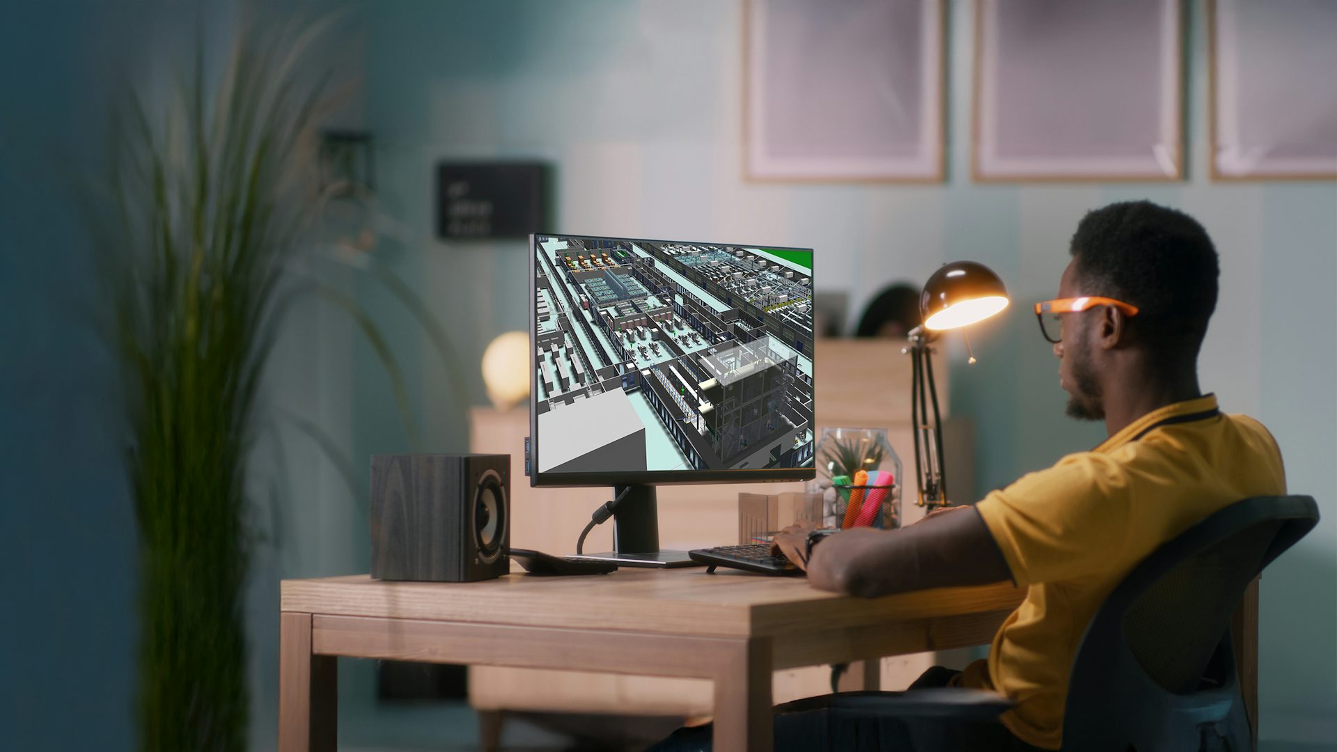 Male engineer reviewing a factory digital twin model in Tecnomatix Plant Simulation software on a desktop computer.