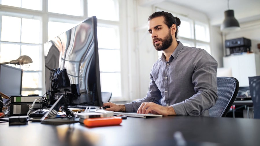 A software developer sitting at their desk and working on the computer.