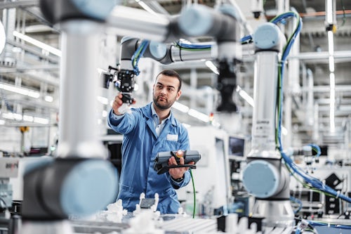 Man calibrating industrial robots with connected services for SMB manufacturing