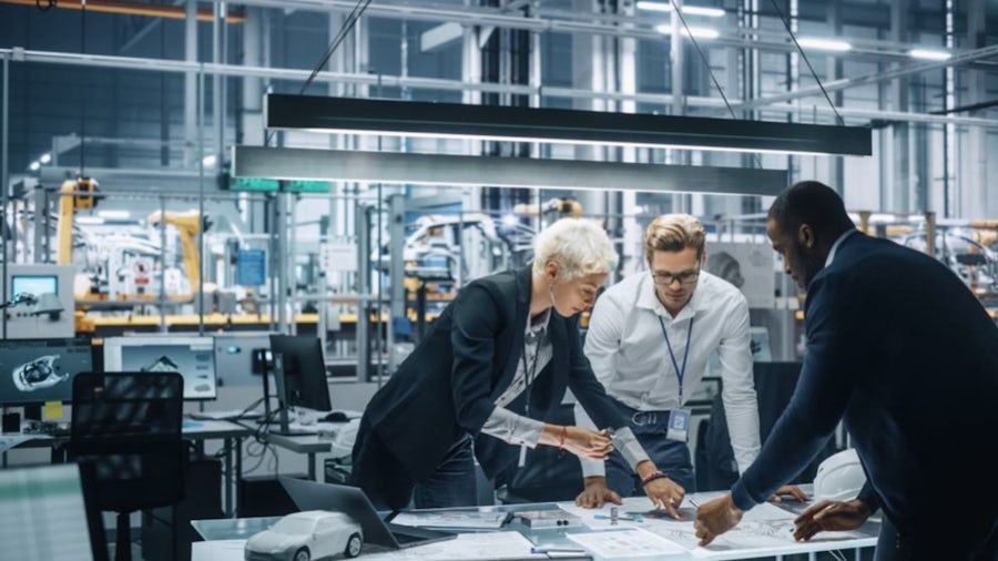 Project managers working on an automotive product near an automotive assembly line