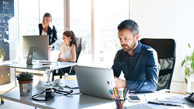 Three members of an electrical systems engineering team working in an office.