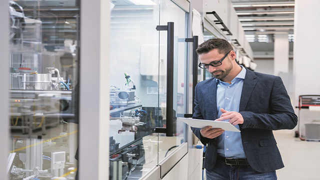 Man in a jeans with a sport coat in a warehouse looking at a tablet