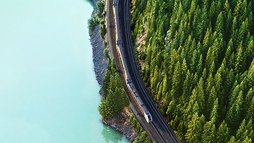 An aerial view of a train on a track next to a body of water.