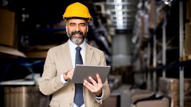 Man holding a tablet wearing a hardhat.
