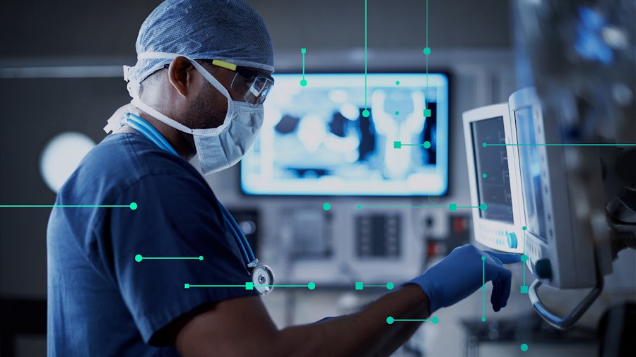 Medical professional wearing scrubs while looking at medical device screen