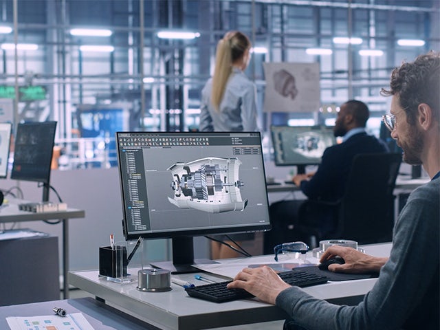Hombre trabajando en un ordenador con software de diseño en una oficina.