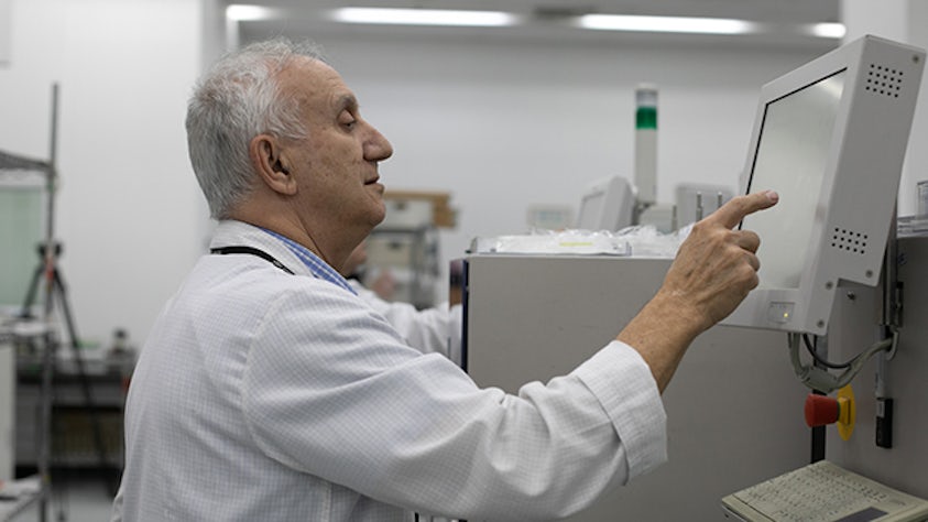 Un hombre en un laboratorio informático tocando una pantalla de la electrónica de conectividad inteligente.