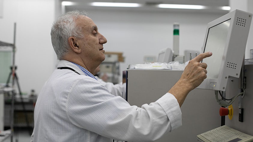 A man in a computer lab touching a screen on the smart connectivity electronics.