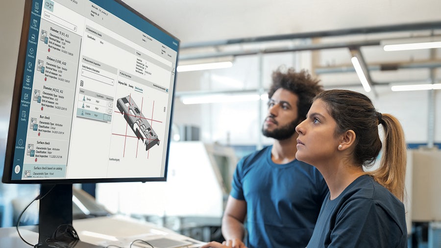 Two workers looking at a screen showing Siemens Opcenter X Quality cloud-based quality management system (QMS) software. 