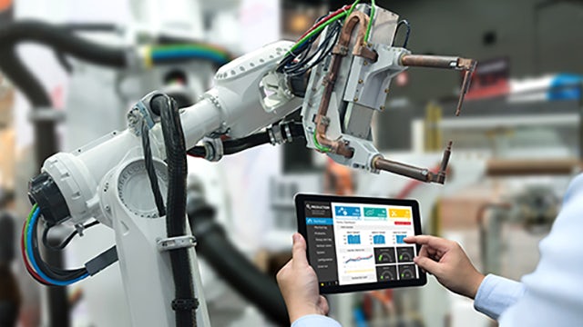 Ein Ingenieur verwendet ein Tablet, um einen Roboterarm für die Automatisierung zu bedienen.