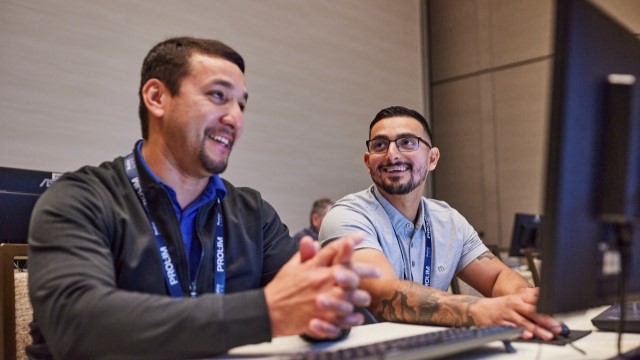 Two people sitting at a desk in front of a computer at Realize LIVE while taking part in a hands-on training session. 