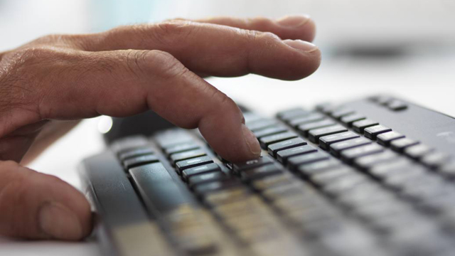 Closeup of a hand typing on a keyboard.