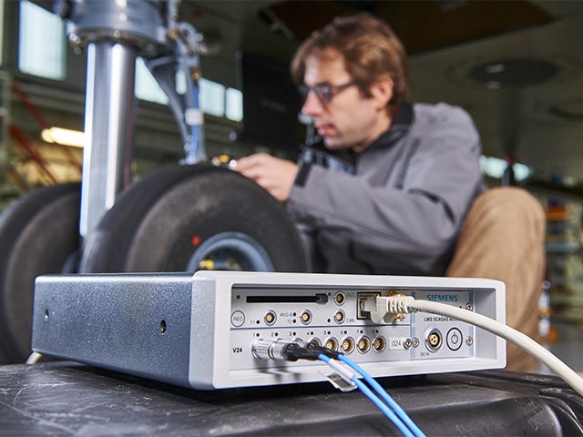 An engineer running a performance test with the help of a Simcenter SCADAS device.