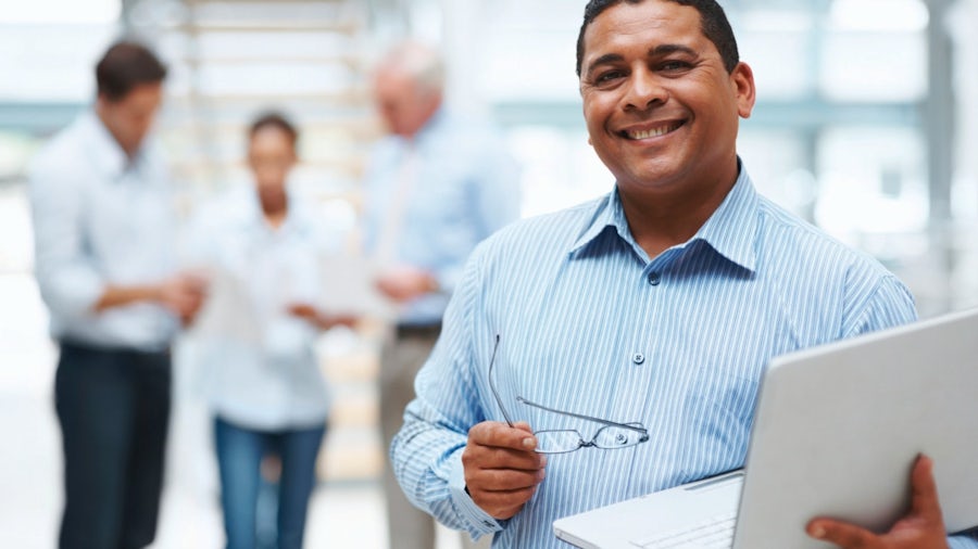 A network engineer with automotive domain experience holding a laptop and collaborating with other engineers in an office.