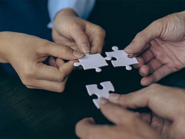 Trzy ręce ludzi trzymające białe puzzle łączą się ze sobą