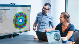 Two people reviewing a dashboard in Simcenter on a computer monitor