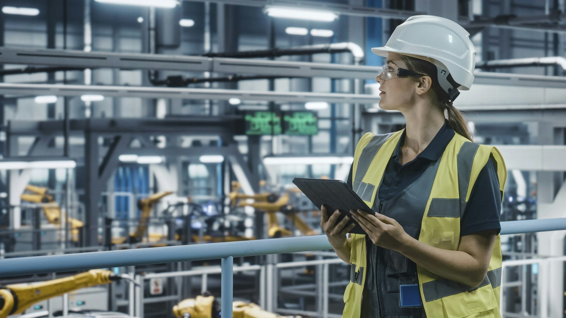 Woman in a manufacturing facility holding a tablet.