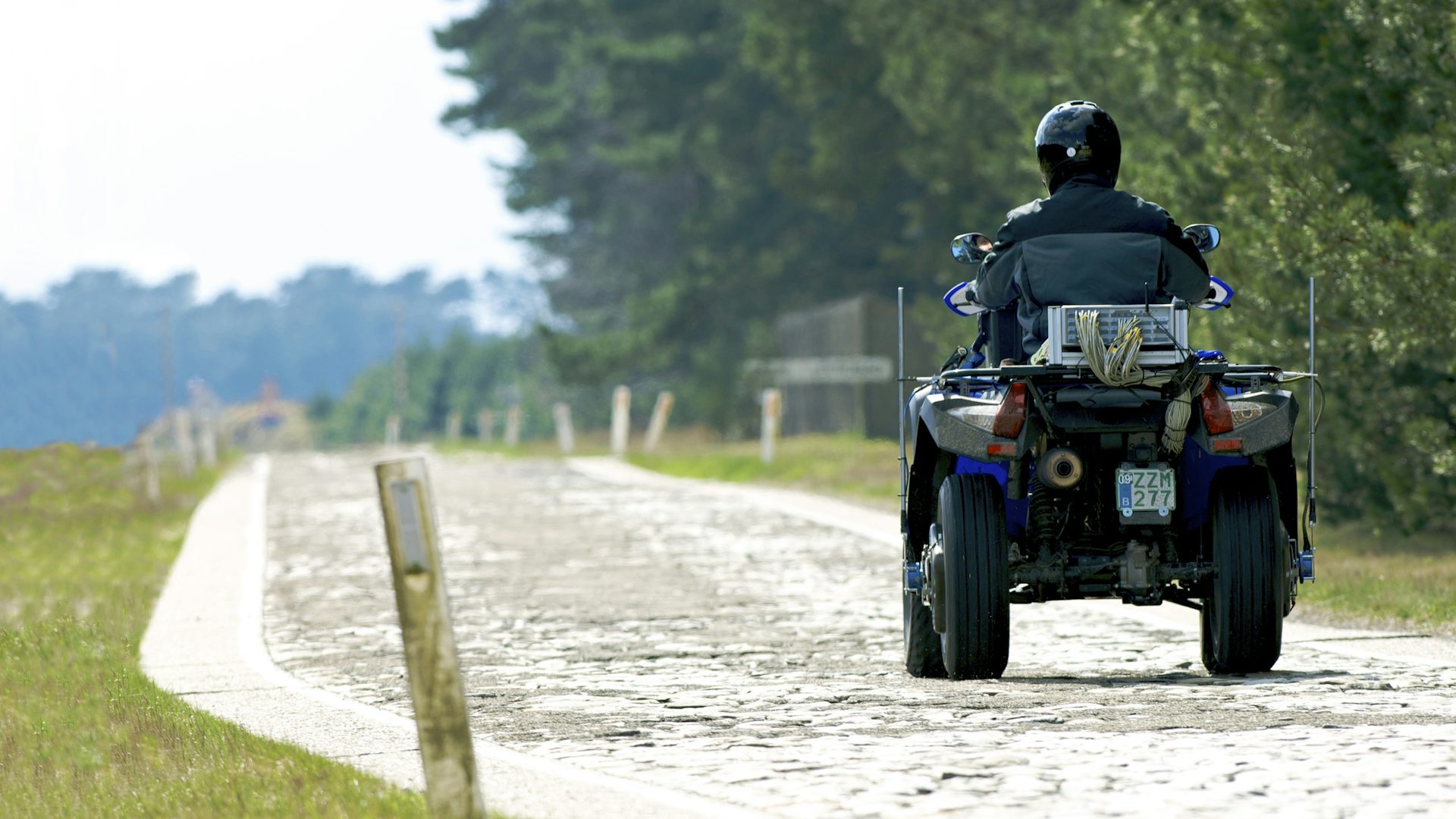 A person driving an ATV down a country road.
