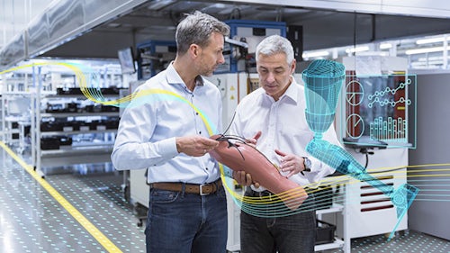Two men in a medical device manufacturing facility holding a prosthetic limb and analyzing data.