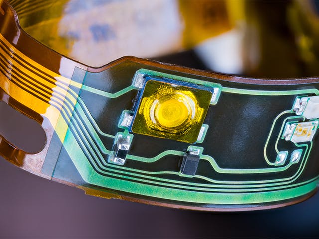 A miniature flexible plastic circuit board with components on it.