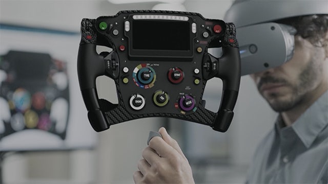 Man wearing Sony VR headset using Siemens NX Immersive Designer software to work on a virtual model of a race car driving wheel.