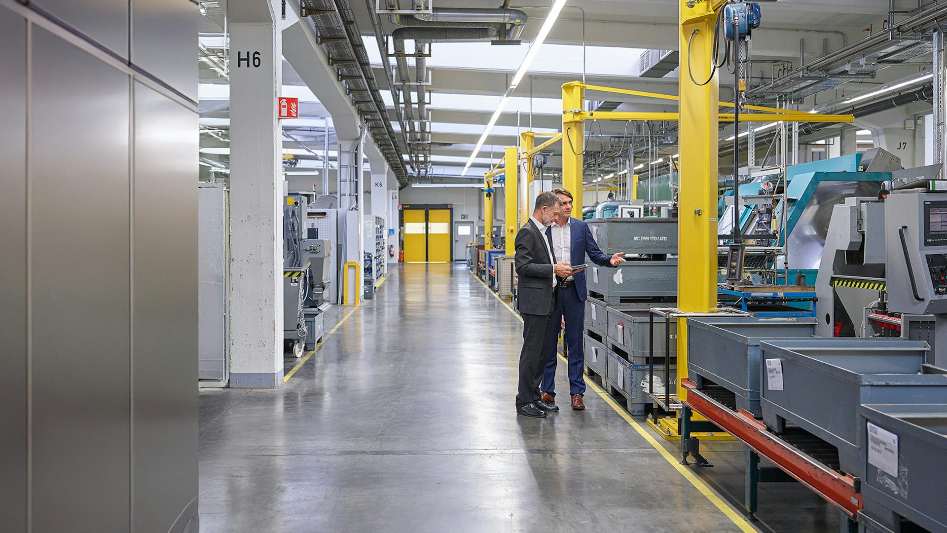 Two men standing in front of equipment at a Brownfield facility.