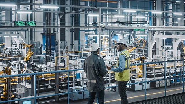 Two engineers in a factory having a conversation possibly about iiot solutions.