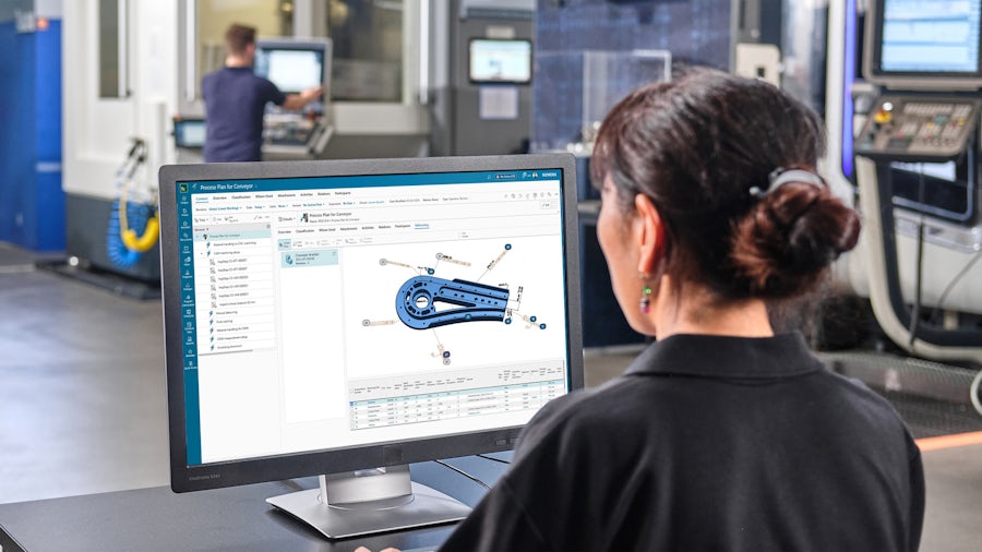 Un ingegnere esamina le specifiche di qualità sul monitor di un computer per la parte di una macchina in officina.