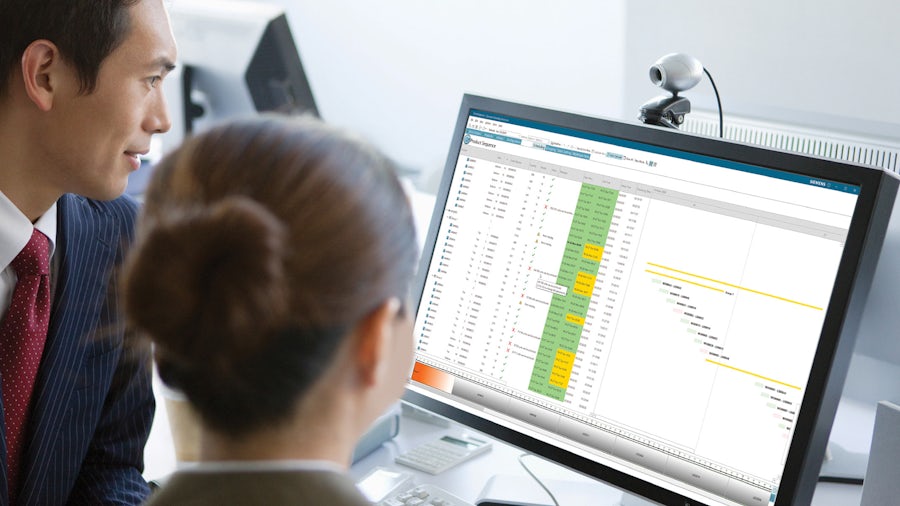 Two workers looking at a production schedule on a computer screen