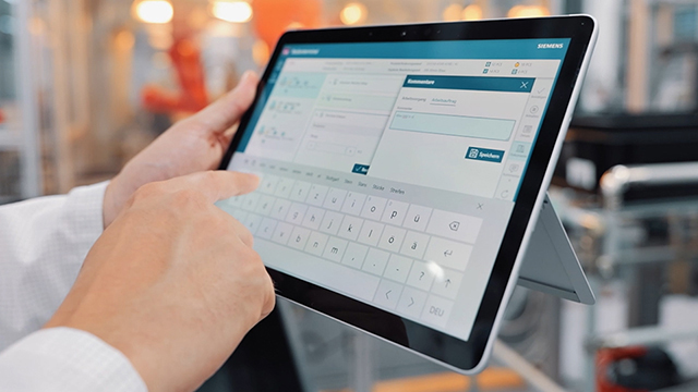 Nahaufnahme einer Person, die ein Tablet hält und darauf zeigt.