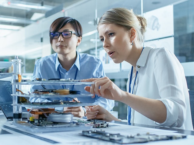 Deux ingénieurs examinent un modèle de circuit imprimé dans une usine d'assemblage de circuits imprimés.
