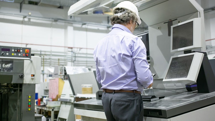 Un dipendente di un'officina meccanica guarda il suo sistema di esecuzione della produzione su un tablet.
